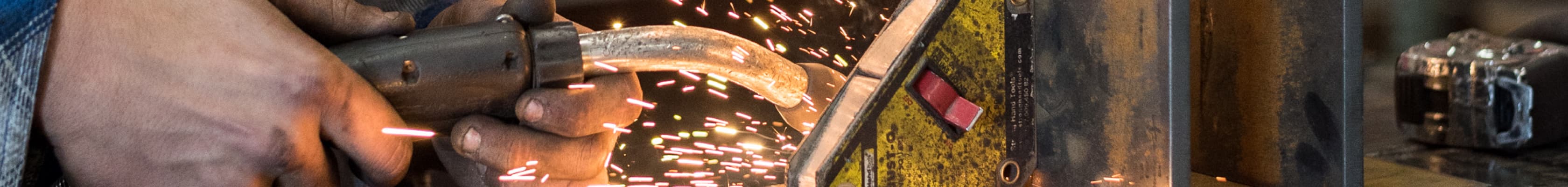 A close up of a man welding steel pieces together