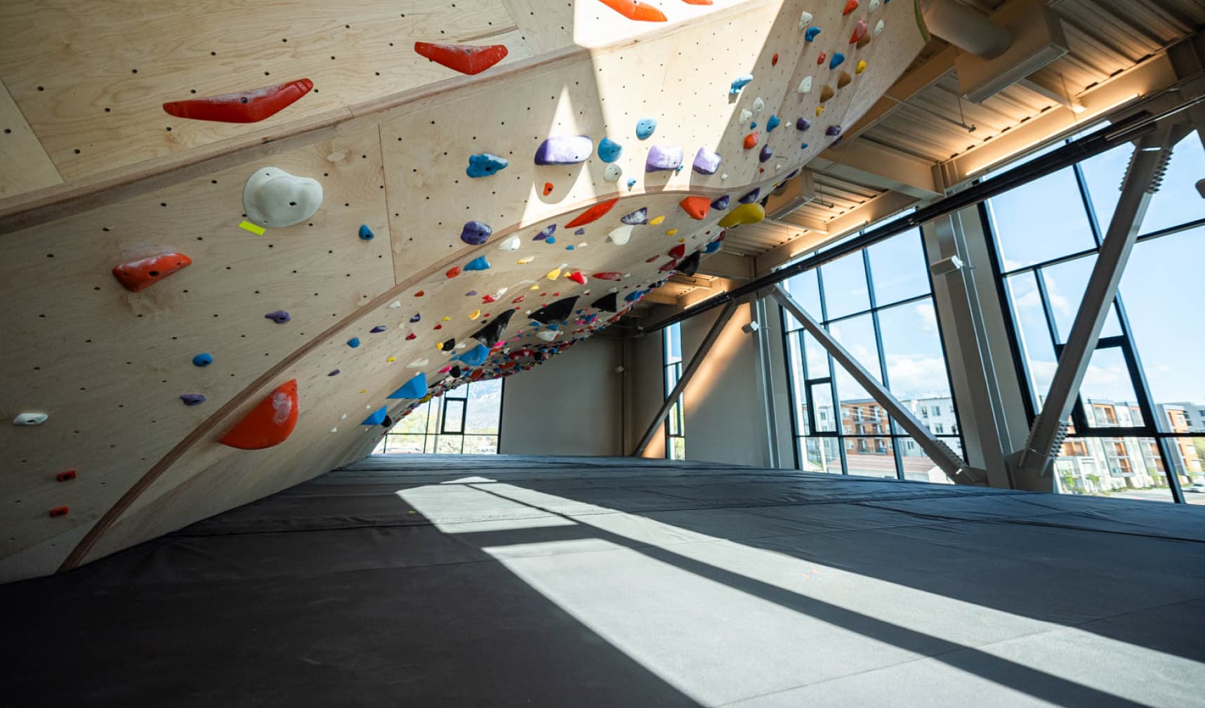 Curving wood climbing wall overlooking a window looking out to Salt Lake City