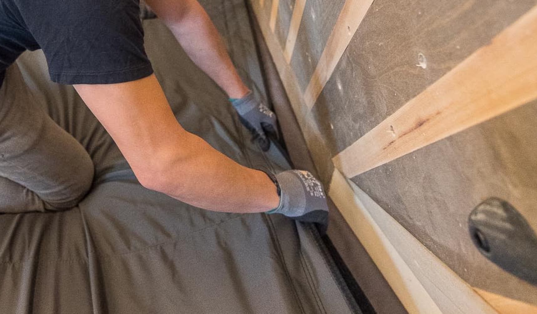 A man attaching a bouldering pad to the bottom of a climbing wall