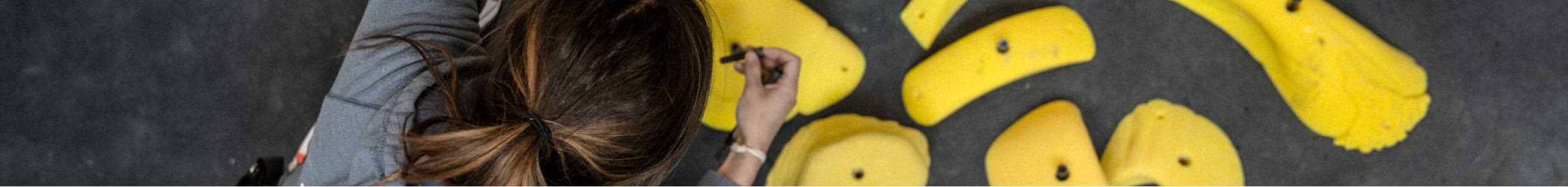 A routesetter organizes yellow climbing holds