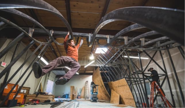 A man climbs on a steel frame for a future climbing wall