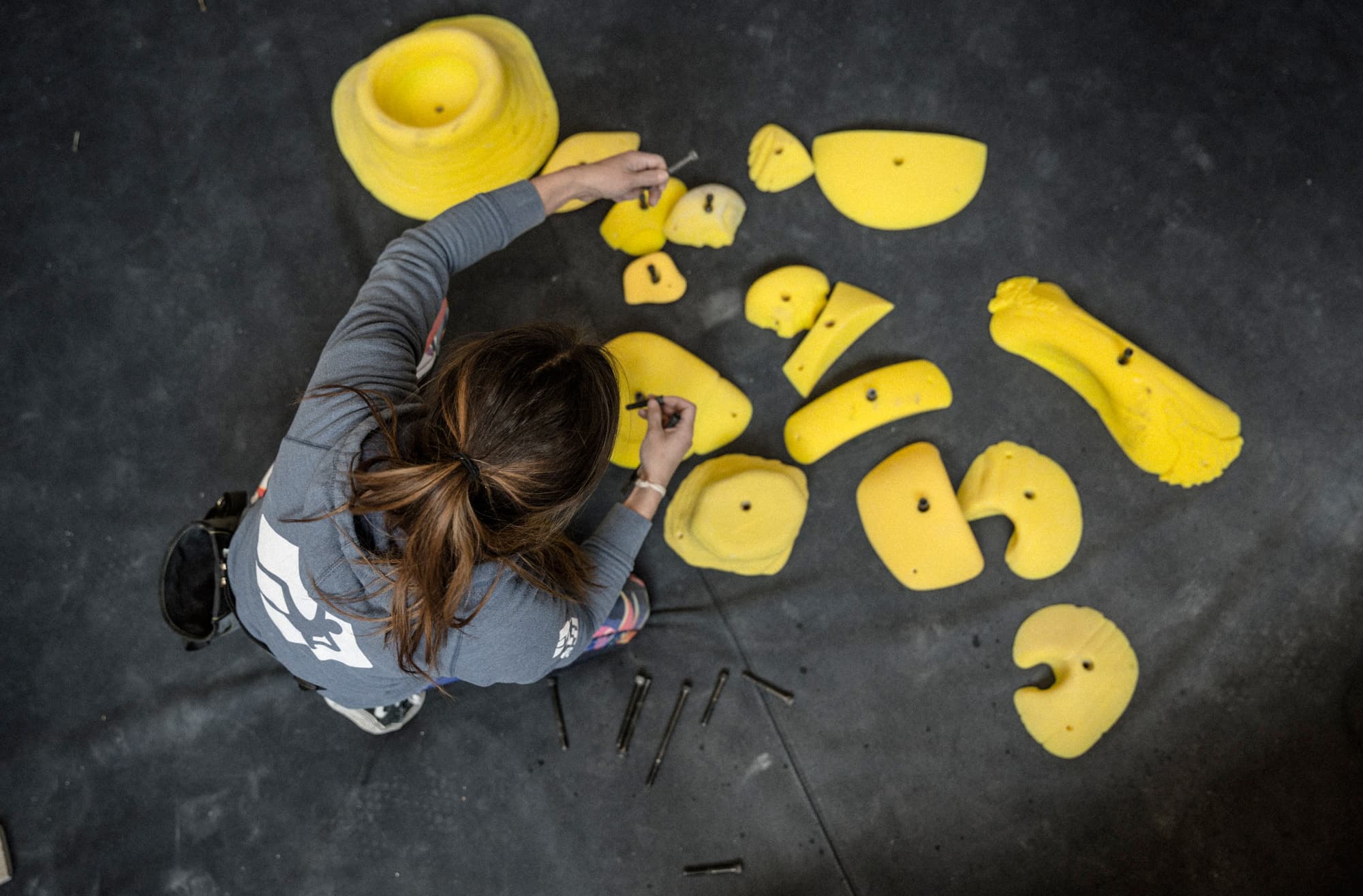 A setter standing over climbing holds supplied by Vertical Solutions