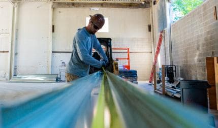A smiling man in a hardhat at a climbing gym construction site