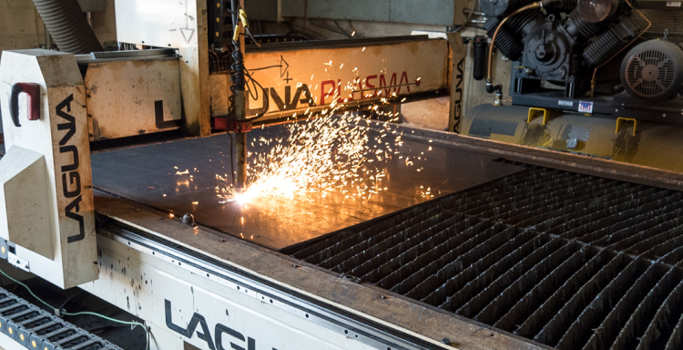 A plasma cutter throwing off sparks while cutting a sheet of steel