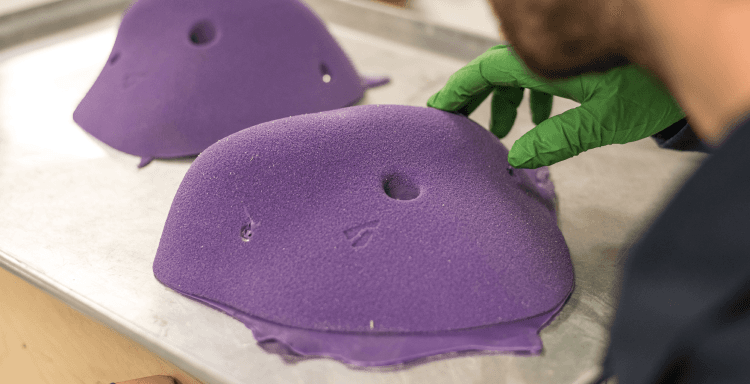 A Vertical Solutions employee inspects a tray of purple climbing holds