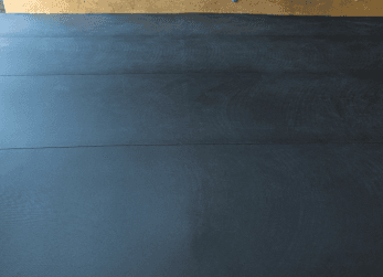 A field of gray bouldering flooring in front of a wood wall