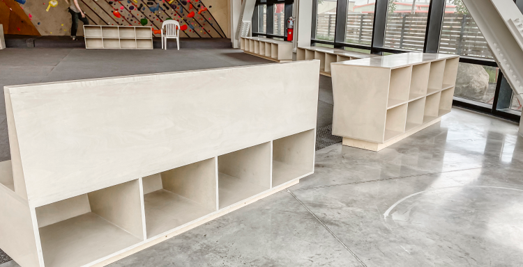 Modern white birch storage benches in front of a climbing wall