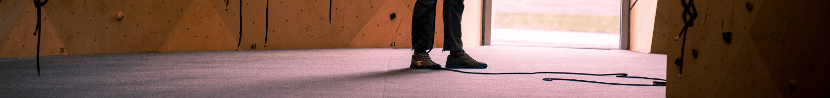 A man stands in front of a window while getting ready to rock climb