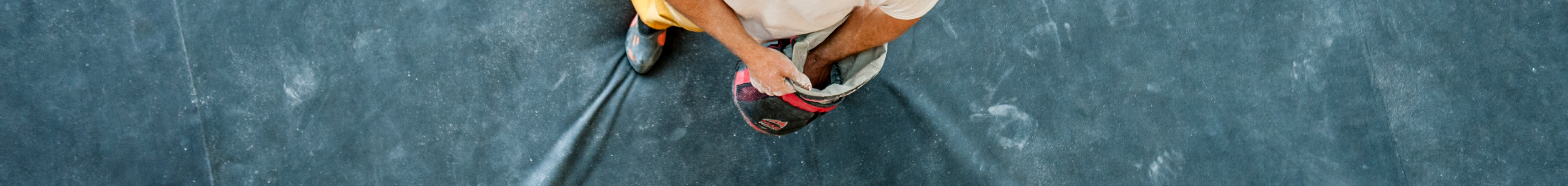 A man dipping his hand into a chalk bucket at a rock climbing gym