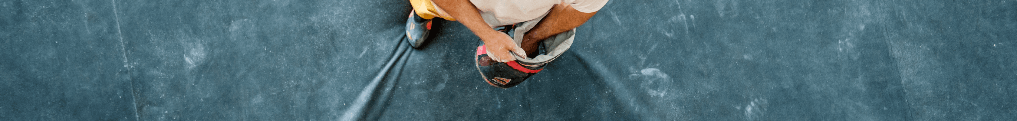 A man dipping his hand into a chalk bucket at a rock climbing gym