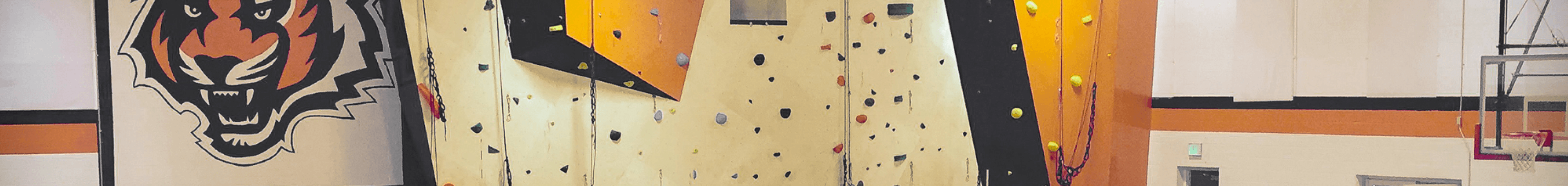 High school rock climbing wall next to a basketball court