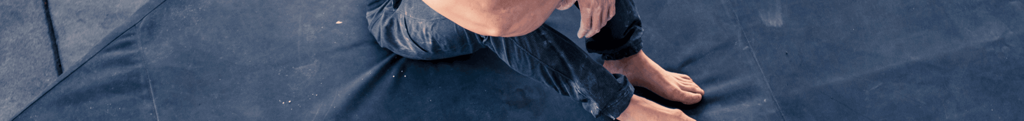 Man sitting on a black bouldering pad 