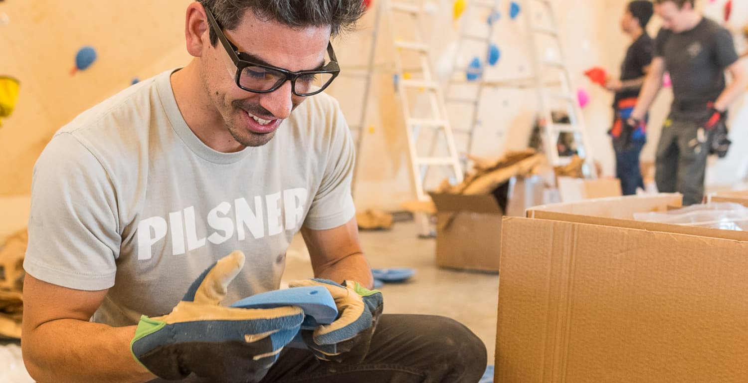 Smiling man holding a blue indoor rock climbing hold