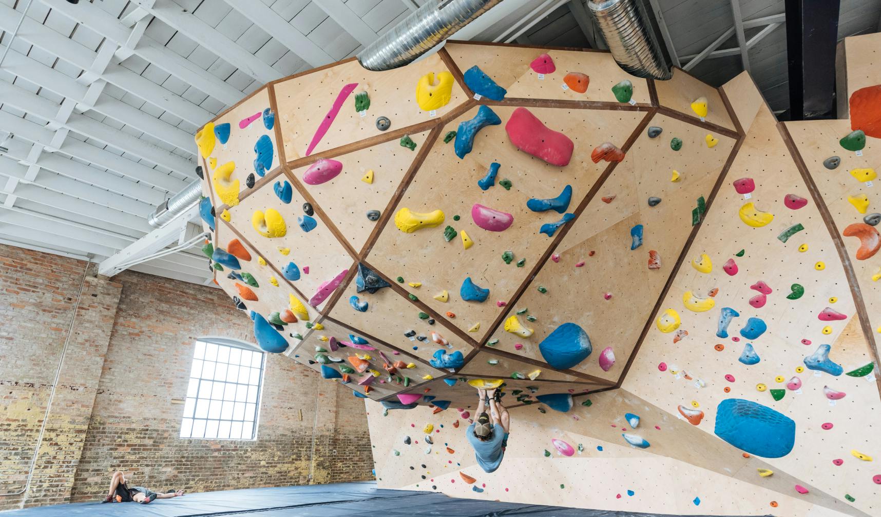 Large unique bouldering wall shape with man climbing
