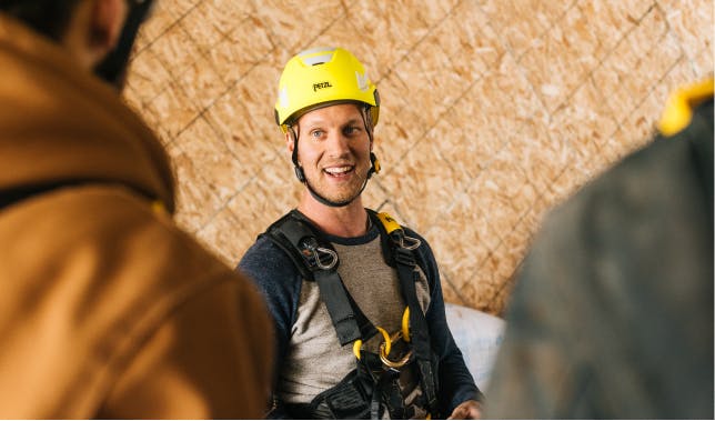 A smiling man in a hardhat at a climbing gym construction site
