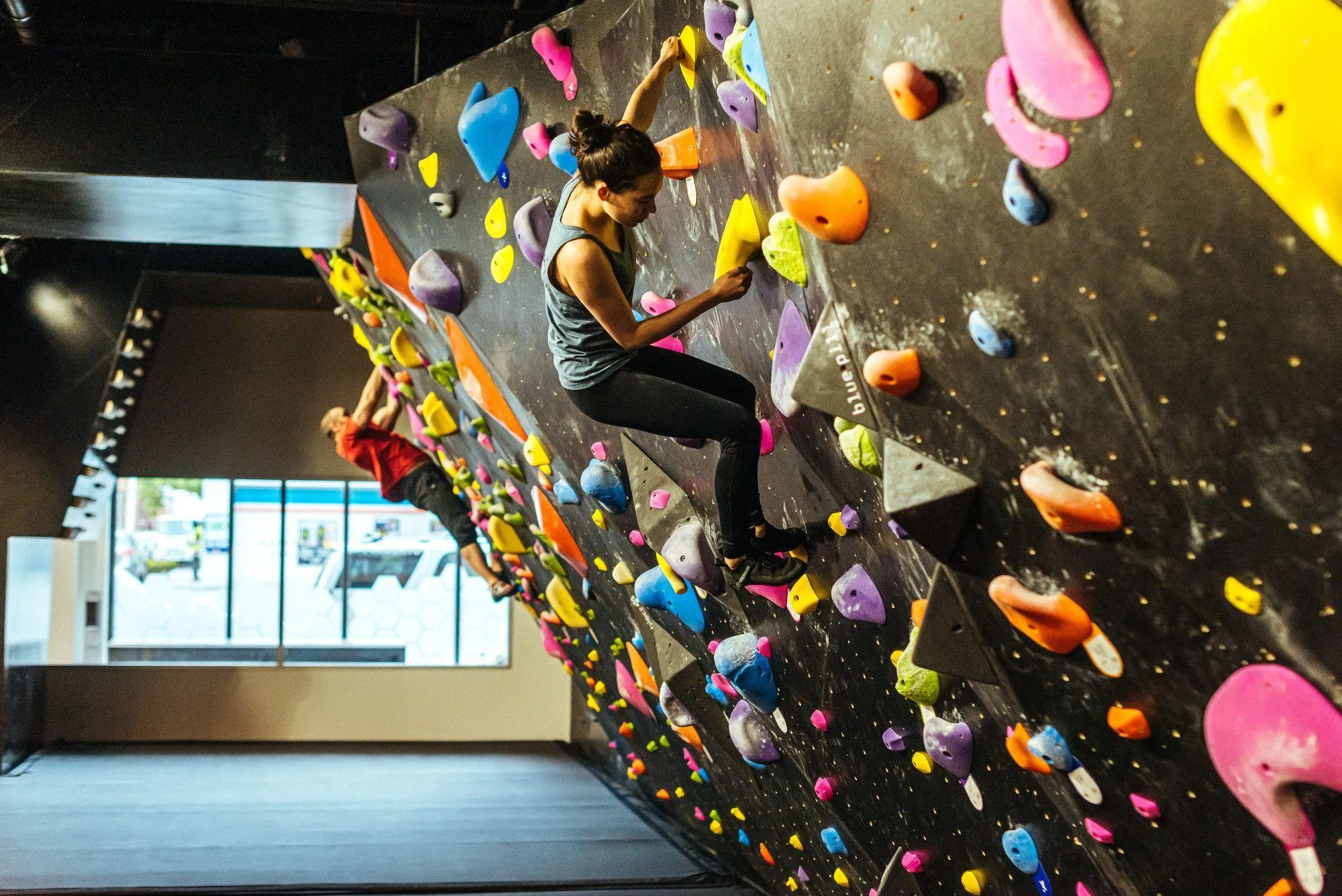 The brightly colored climbing holds really pop against the black bouldering wall, giving the space a unique aesthetic.