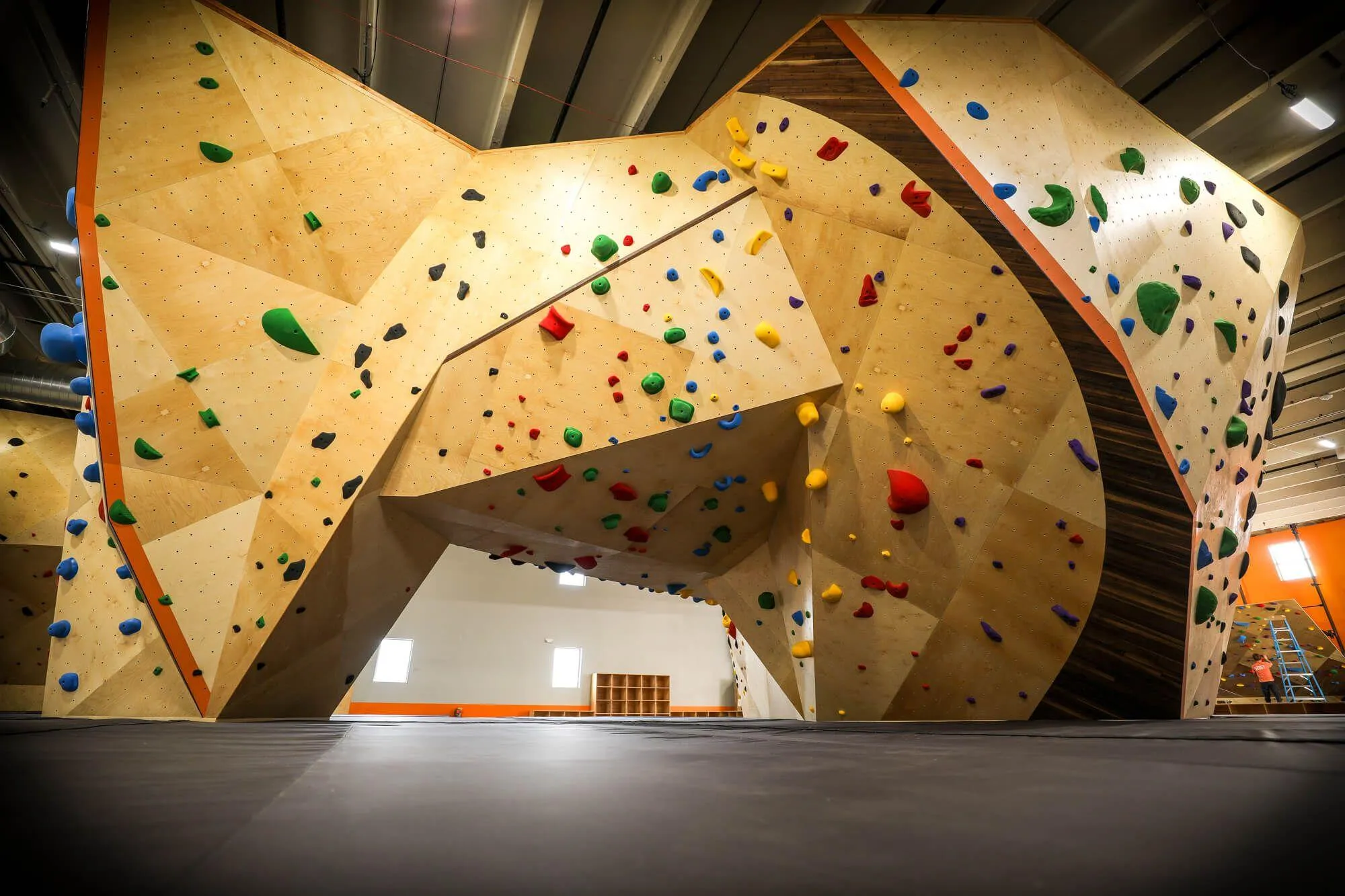 A floor-level view showing the ultra-clean install of Habit Flooring at this climbing gym, tightly surrounding the center boulder and providing safe deceleration from the extreme heights.