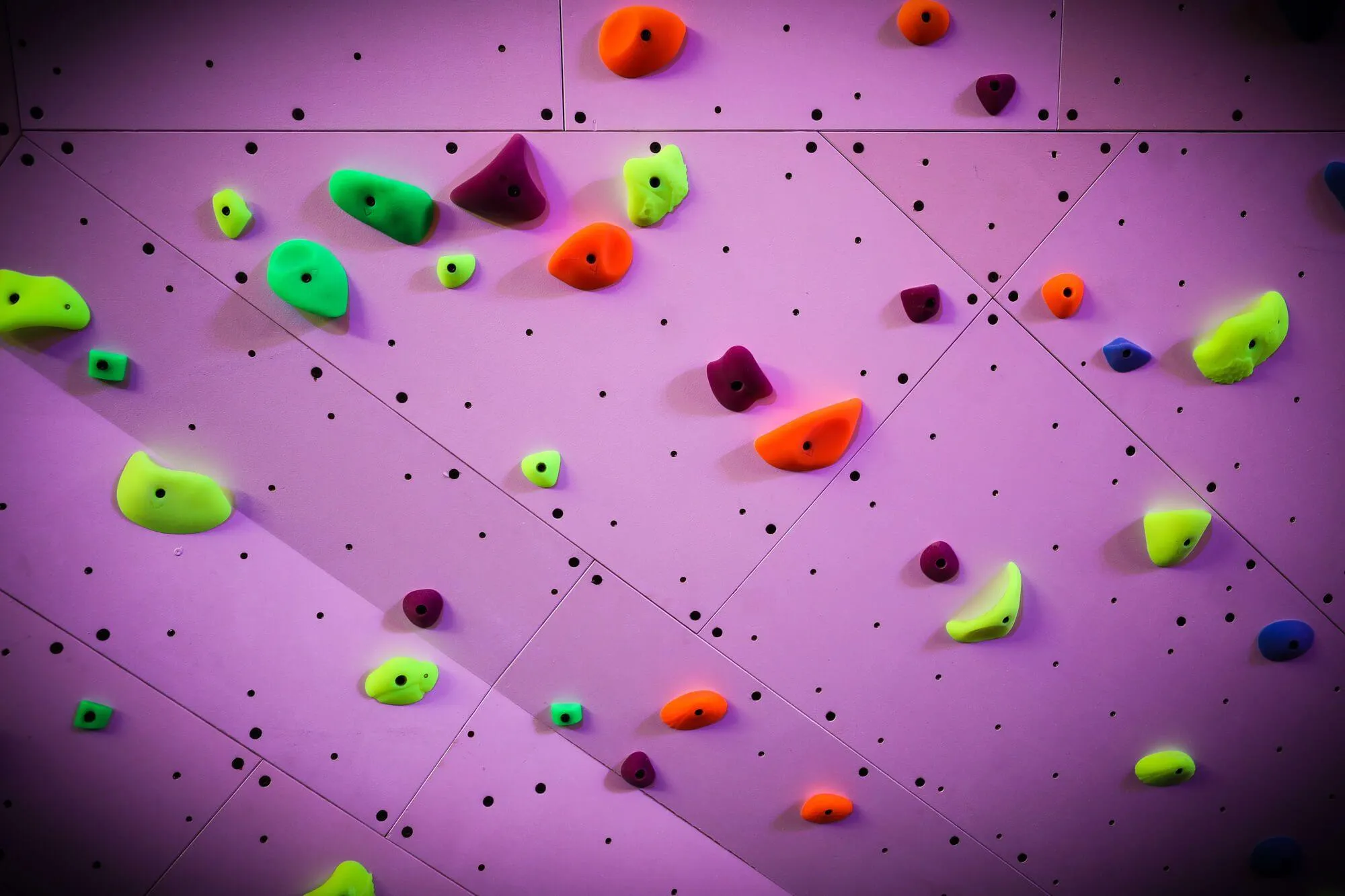 A closeup view of how perfectly our SLM wall panels are manufactured to come together onsite for a clean and consistent appearance. It's also obvious in this image to see how much the custom-colored climbing holds pop against the wall paint.