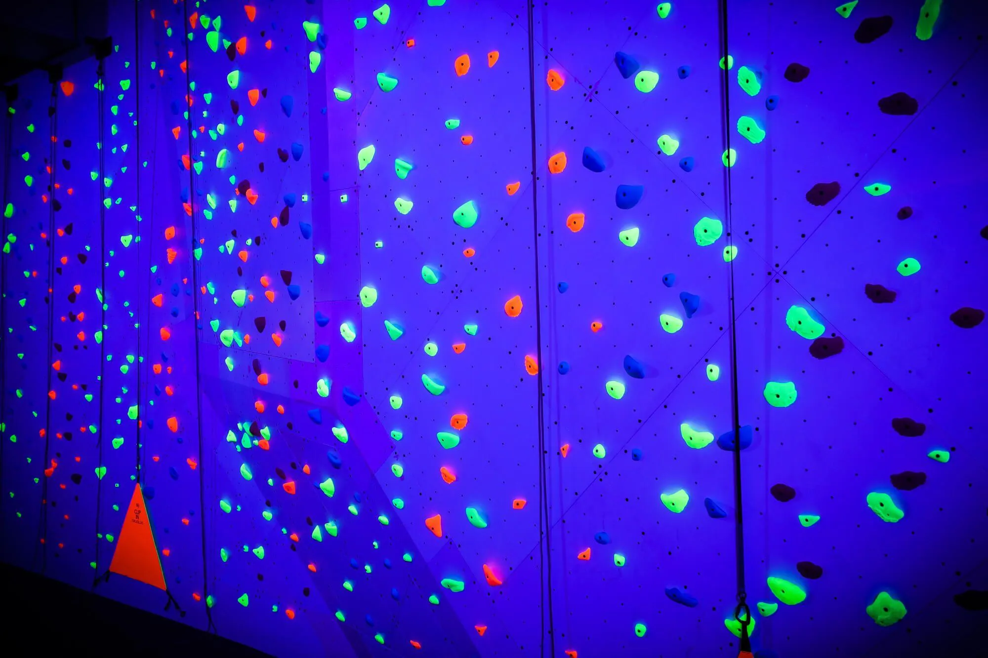 White during the day, and a vibrant purple when in the dark under blacklight. The owners didn't want to have typical florescent lighting necessary for their nighttime climbing, which is located adjacent to a roller rink. So they sought an option that we were thrilled to deliver: a custom application of blacklight coating.