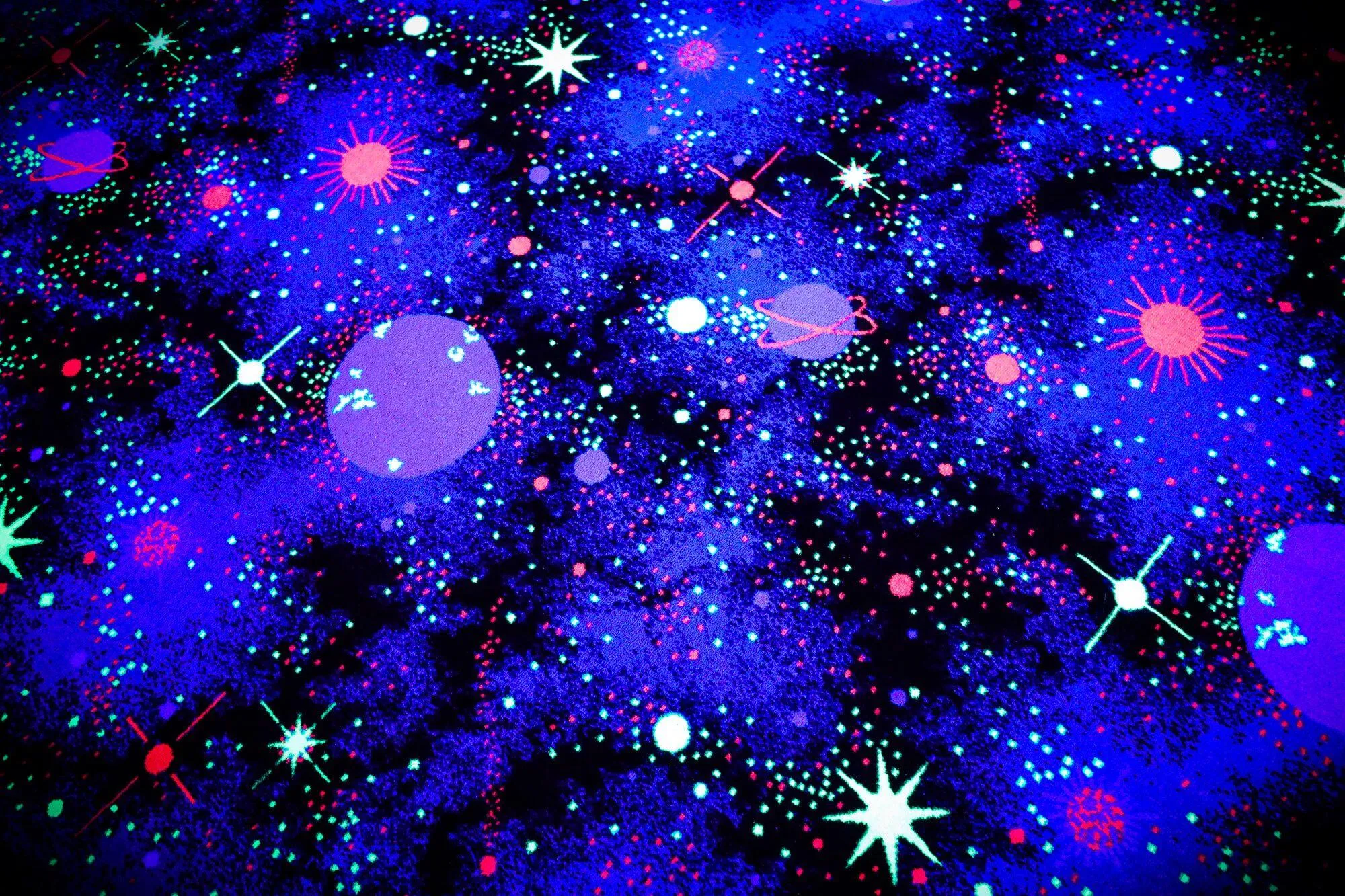 A closeup view of the carpet surrounding the climbing walls, chosen to specifically accentuate and pop when under blacklight. The SLM blacklight climbing walls and special blacklight climbing holds that we manufactured creates a very similar look!