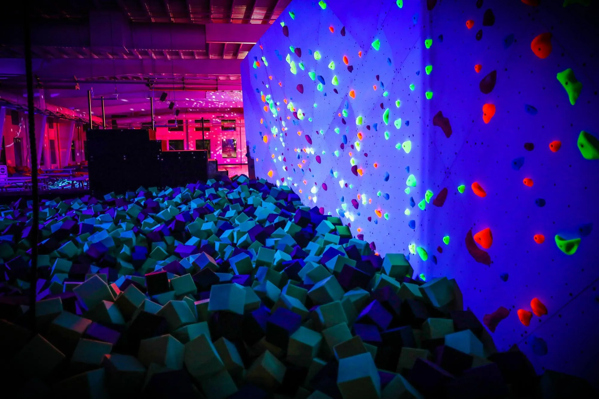 A view of the foam pit bouldering wall that we built under blacklight, with the adjacent roller rink in the background. Specialty lighting was a main theme for the owners of the facility so we had to come with our A-game to contribute.