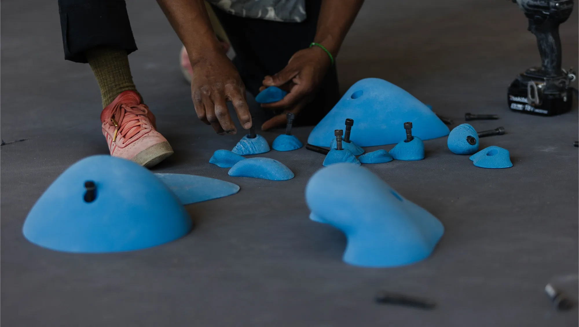 Blue climbing holds being prepared for installation